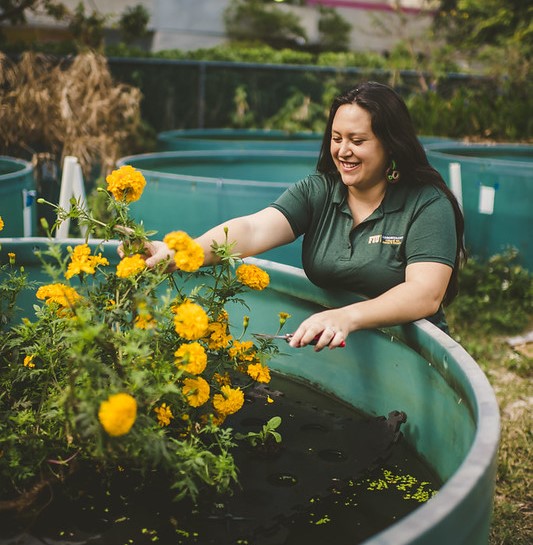 woman smiling next to a water tank with floating marigolds