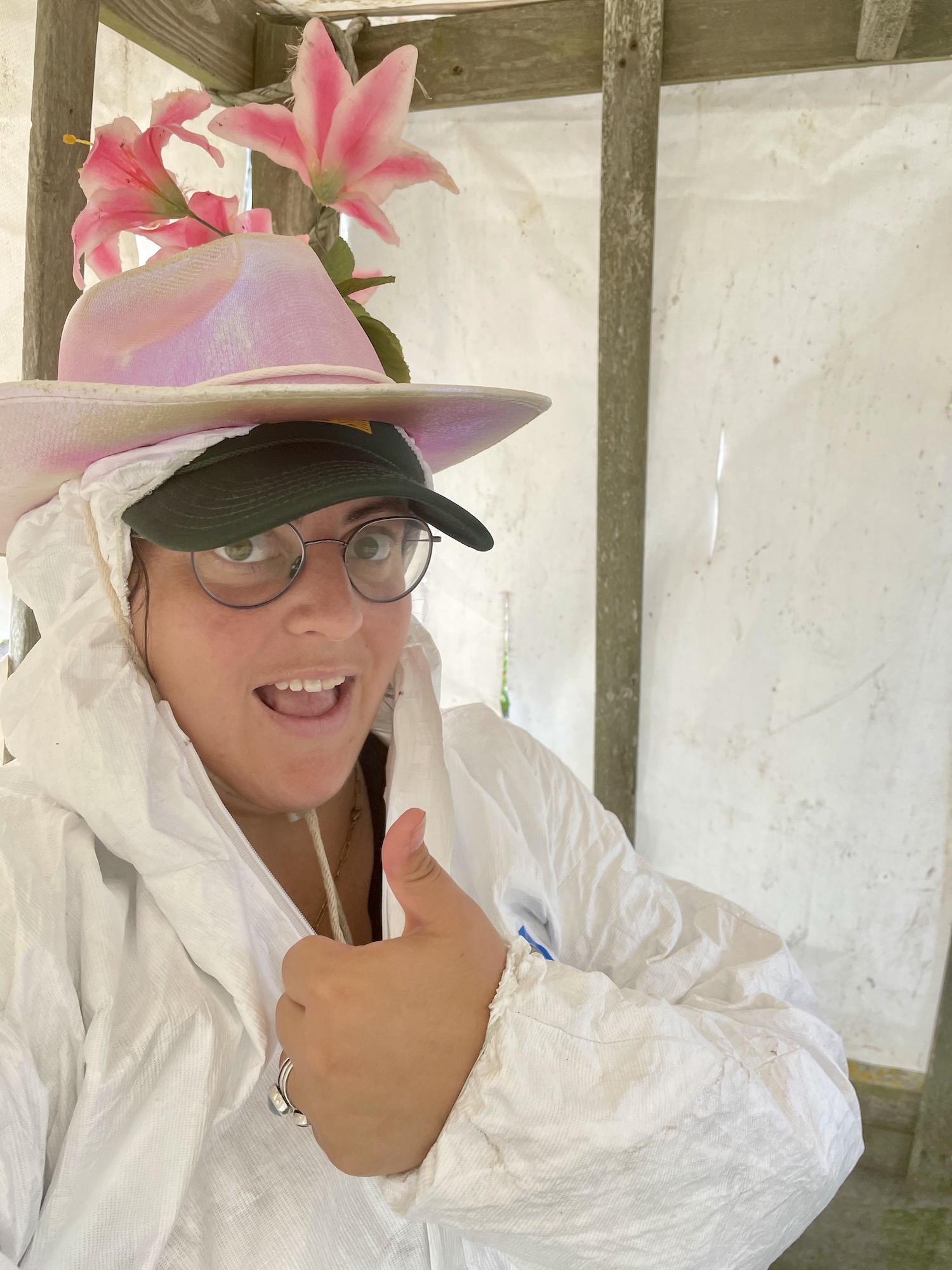 woman in white full-body suit with a sparky cowboy hat adorned with flowers. 