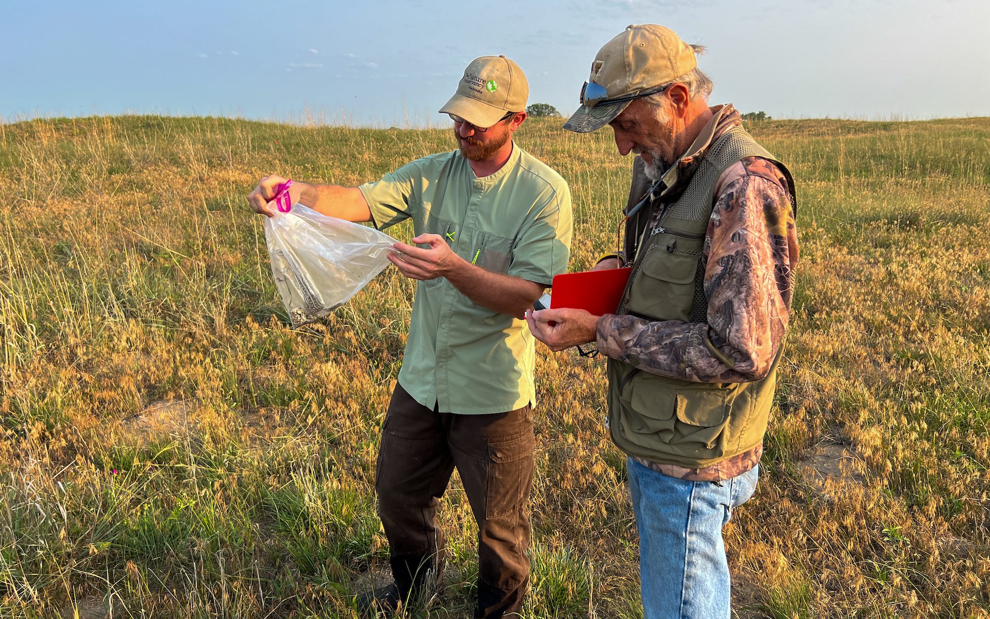 two men holding a groundsquirrel in a plastic bag