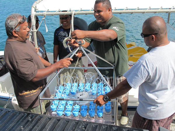 Palauan residents assist scientific operations at Palau International Coral Reef Center by positioning a 350 lb, fully charged Remote Access Sampler (RAS) into the boat. Scientists from Woods Hole Oceanographic Institution and Palau International Coral Reef Center are using the RAS to collect water samples from Palau’s reefs. Analysis of the water samples provides critical information for researchers determining levels of acidification. Photo: Cohen Lab, WHOI
