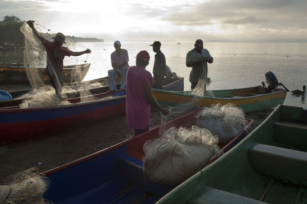 Fishermen, at dawn after a night of fishing on Samana Bay, tend to their nets and catch at the town of Sanchez, Dominican Republic. Healthy and well-managed fisheries enhance a nation's adaptability and disaster resilience. Photo credit: Mark Godfrey © 2009 The Nature Conservancy