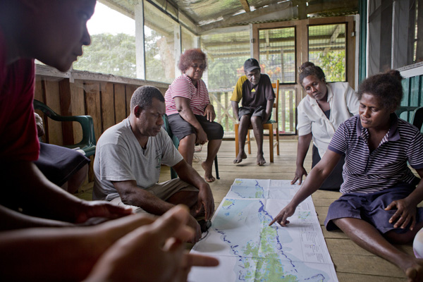 Willie Atu, Project Manager for TNC's Solomon Islands program showing a map of the conserved and threatened areas of the Solomons to the Mothers Union (a group of Kia women who have worked with the Conservancy to raise conservation awareness). Photo: © Bridget Besaw