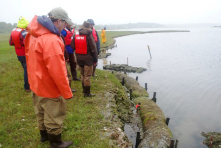 Scientists and engineers assess the degrading shoreline of the Narrow River.