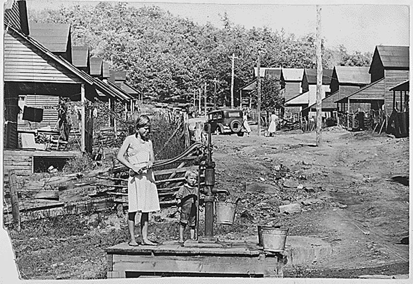 Pumping water by hand in 1942 from the sole water supply in this section of Wilder, Tennessee, in Fentress County (Tennessee Valley Authority). Photo in the public domain from Franklin D. Roosevelt Presidential Library and Museum via Wikimedia