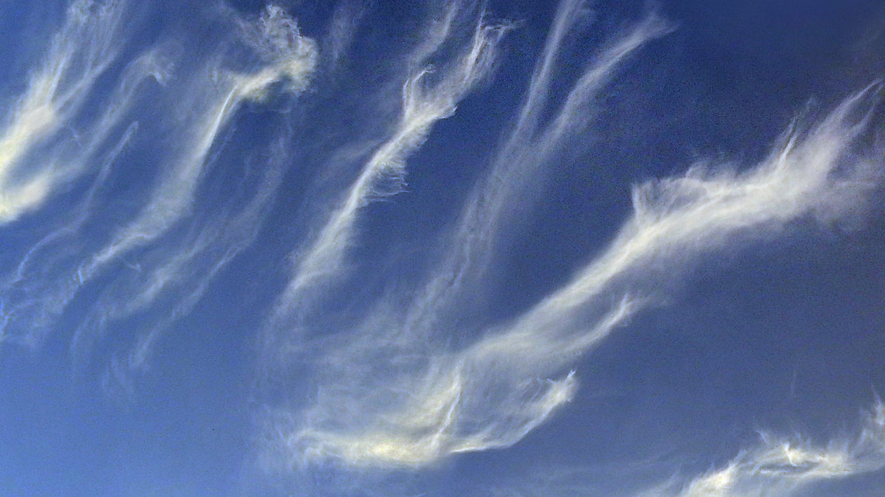 wispy white strings of clouds on blue sky