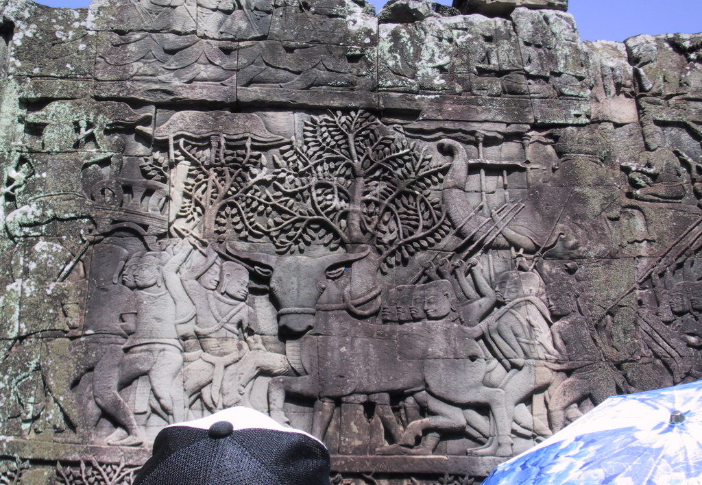 carvings on a stone wall of a bull-like animal and people