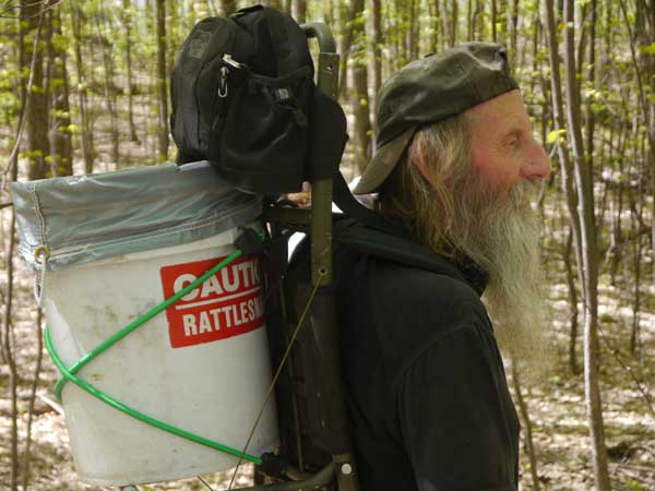 Trained volunteer and herpetology enthusiast Jim Wilson backpacks out a bucket of rattlesnakes. Photo: Matt Miller/TNC