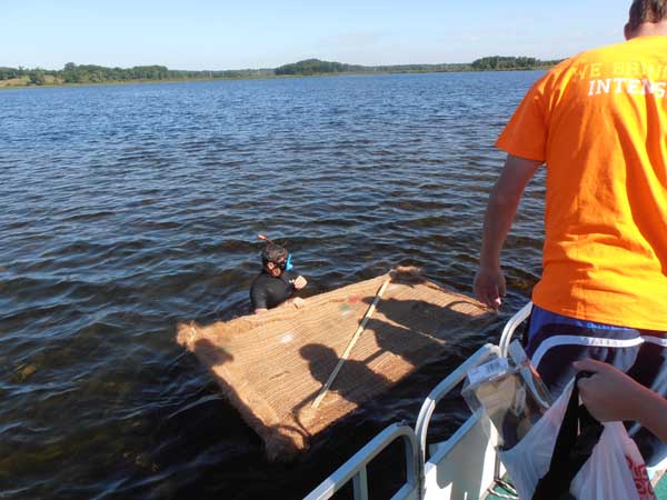 Students of Dr. Tim Gerber install coconut mats implanted with native plants on the bottom of Lulu Lake to restore areas where weeds have been removed. Photo: Jerry Ziegler/TNC