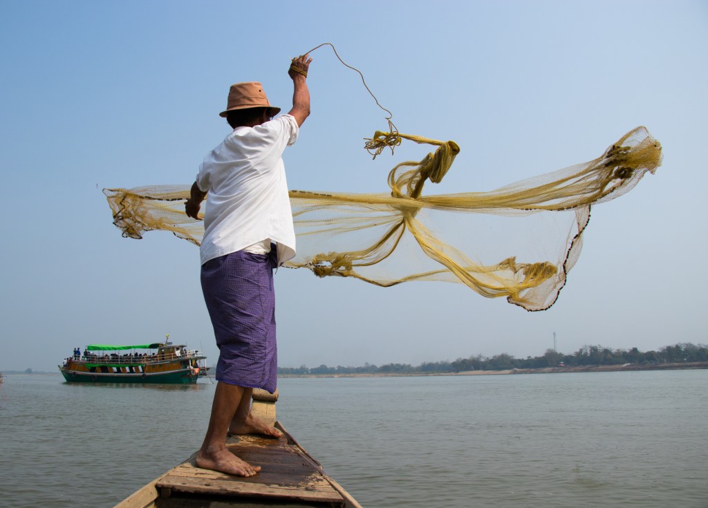 Young man using a throw net to catch fish in rural Cambodia Stock