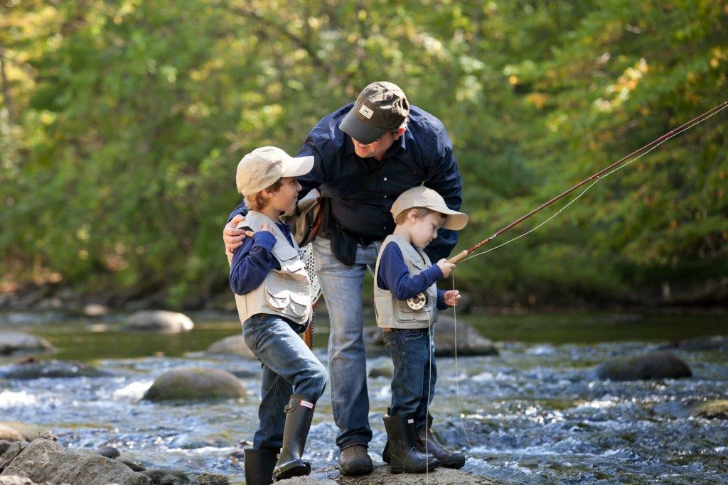 two kids with a man fishing