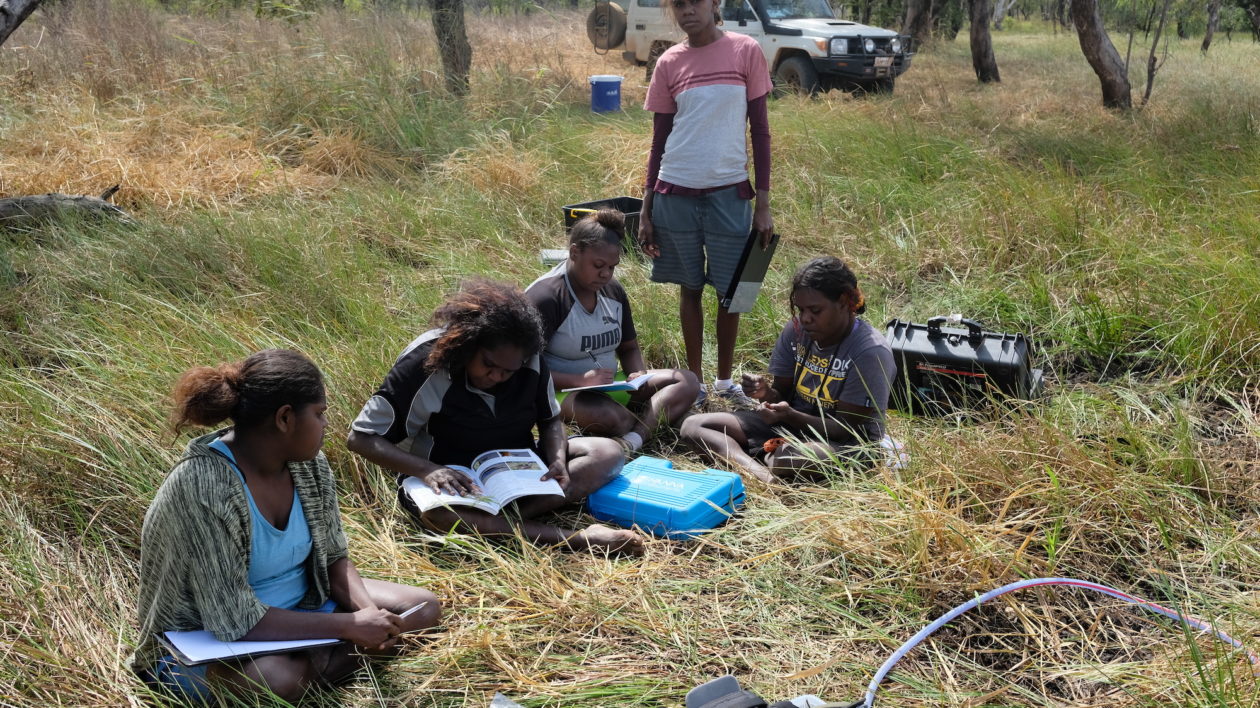 rangers sitting on grass with scientific equiptment