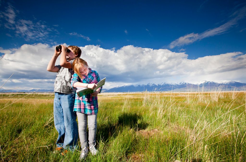 boy and girl in meadow wth binoculars