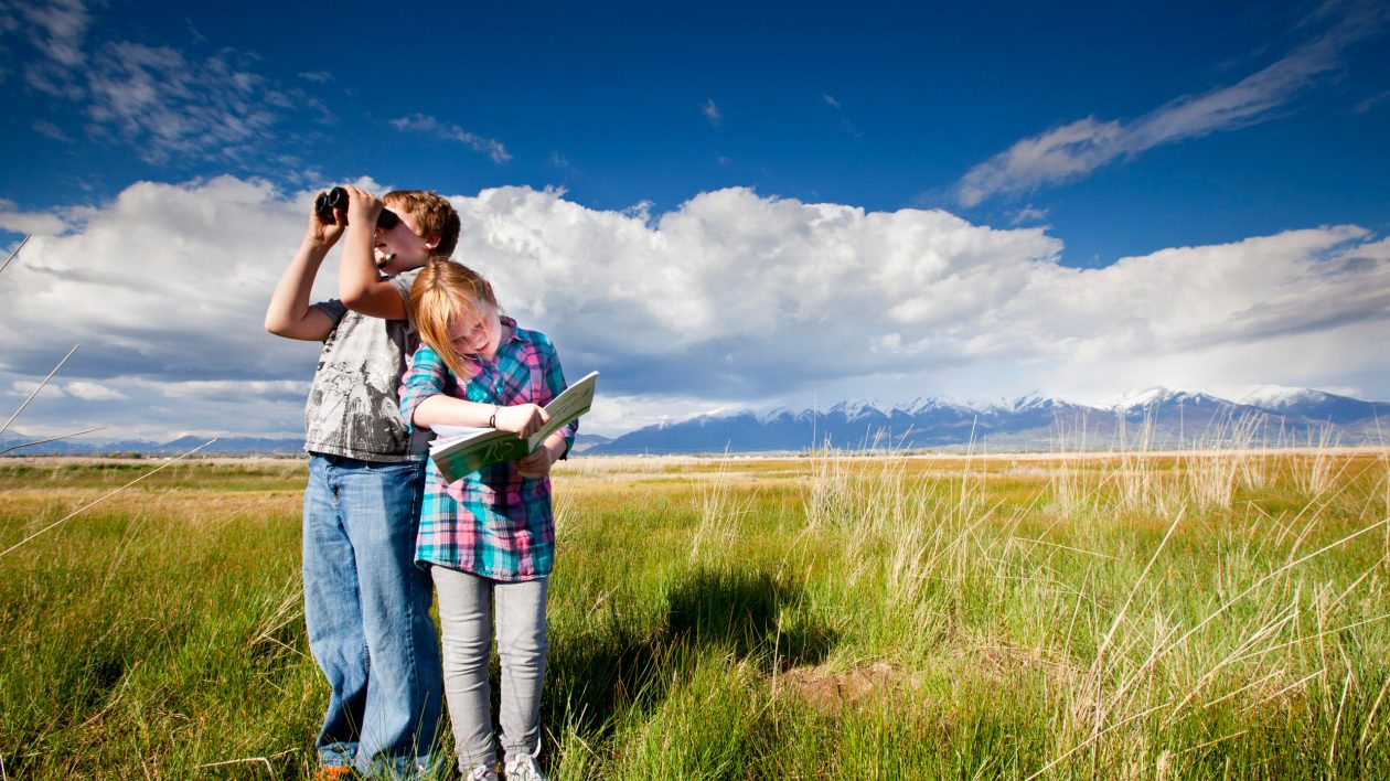 boy and girl in meadow wth binoculars