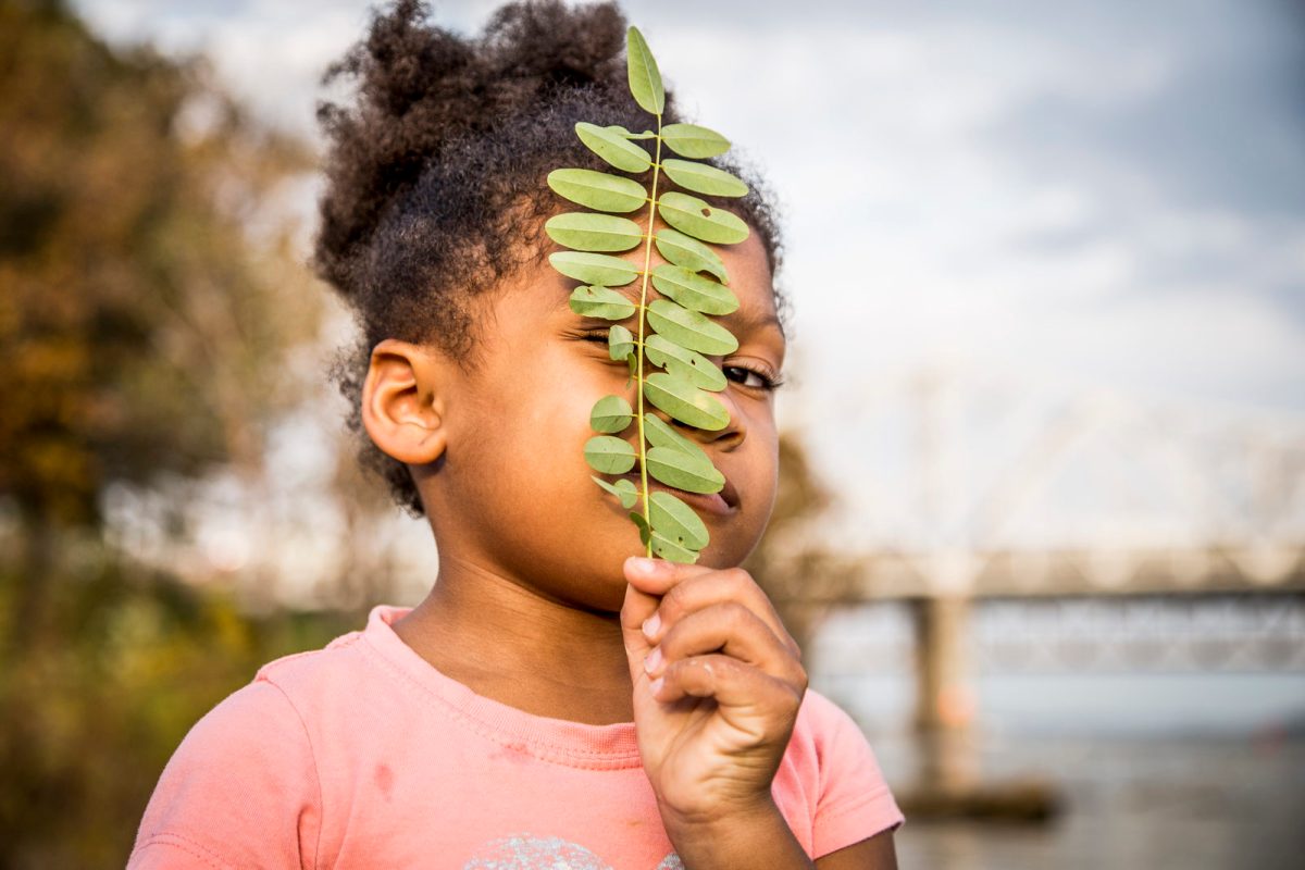 young girl looking through leaves
