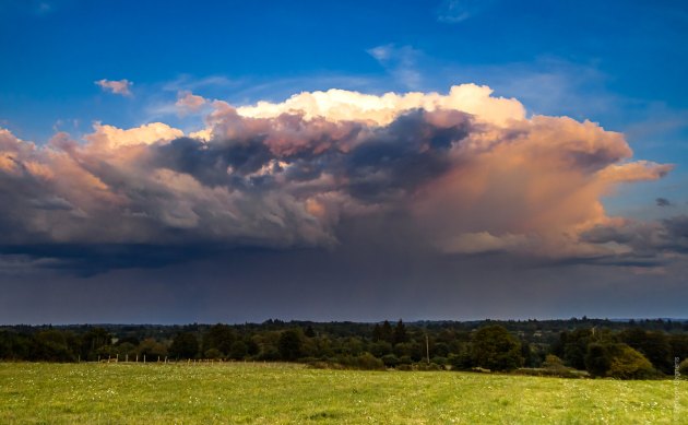 green field with big dark rain clouds