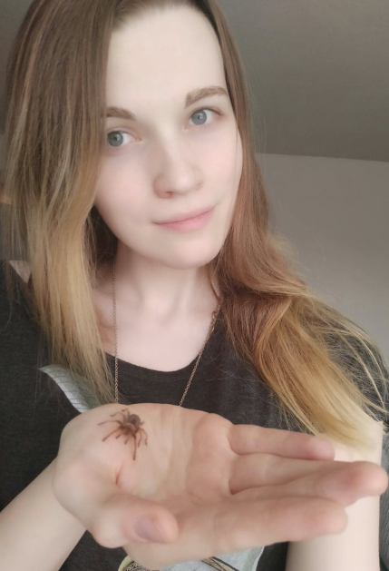 woman holds a small tarantula in her hand