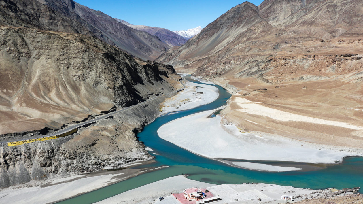 two rivers joining amid brown rocky mountains