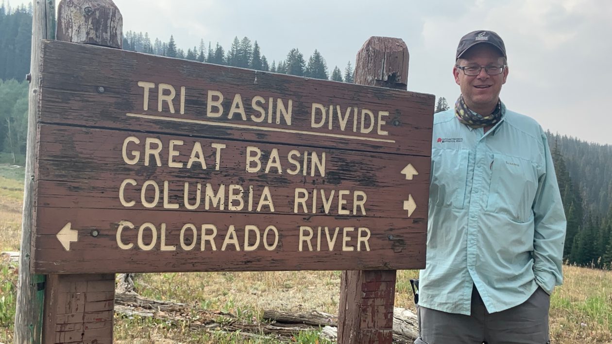 man standing next to a sign and smiling