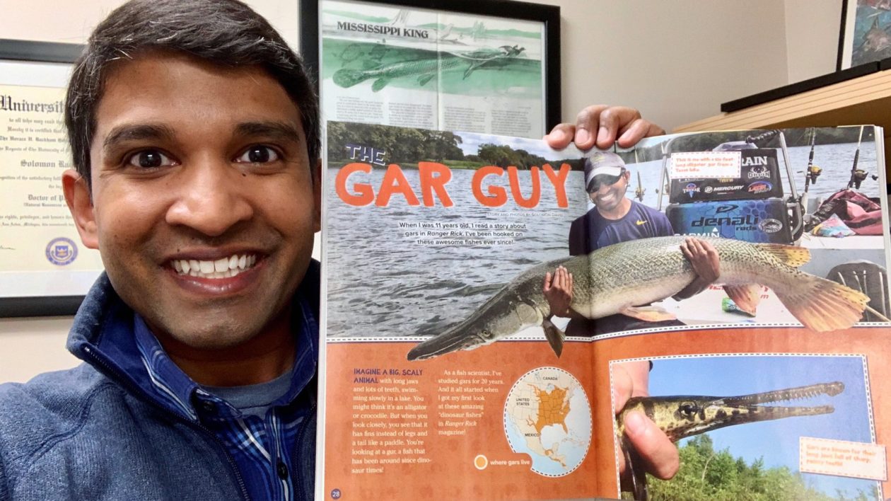 man smiling holding a magazine