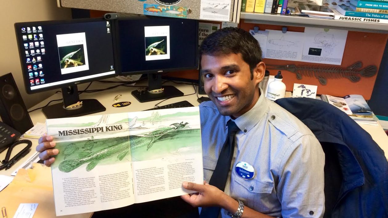 man sitting at a desk holding a magazine