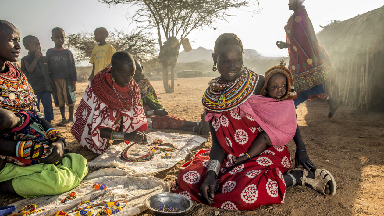 women sit on a mat with bead bracelets