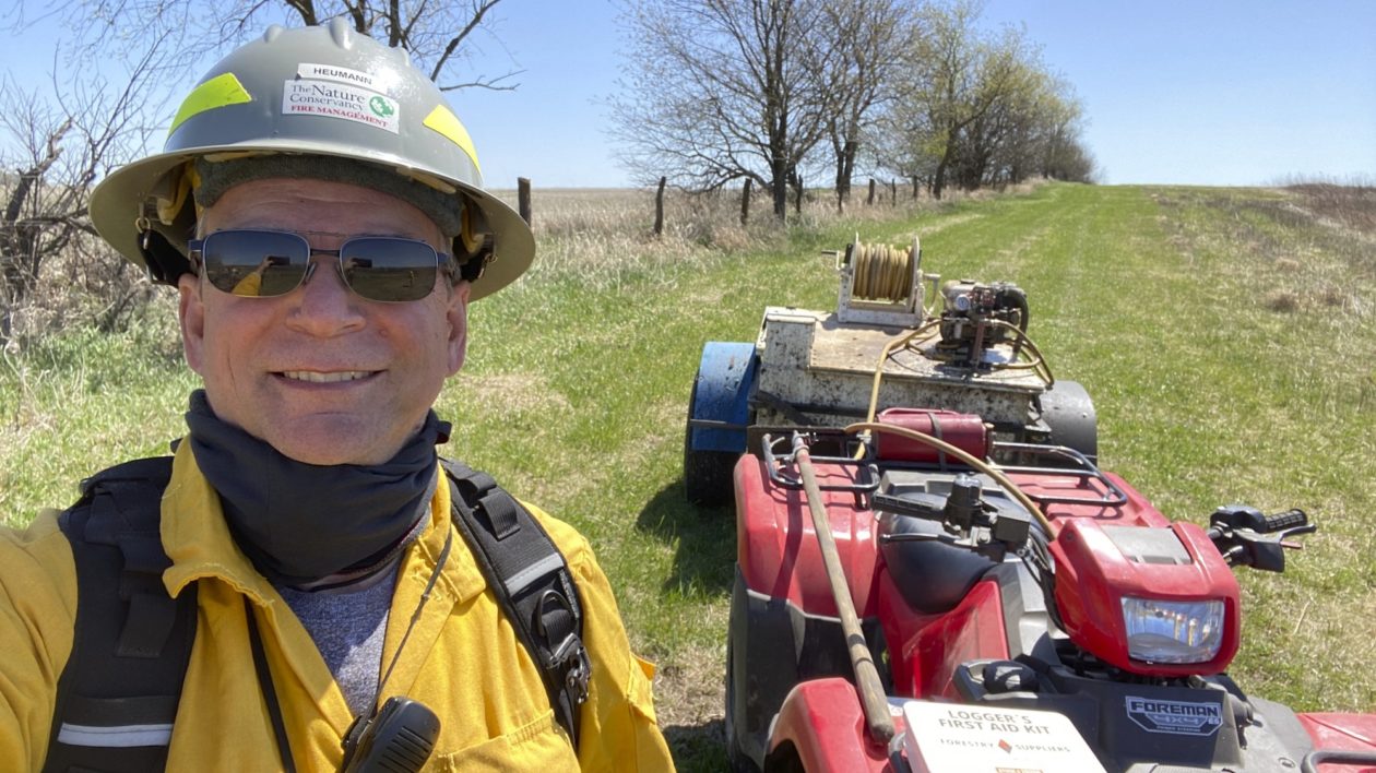 man smiling at camera with machinery behind him