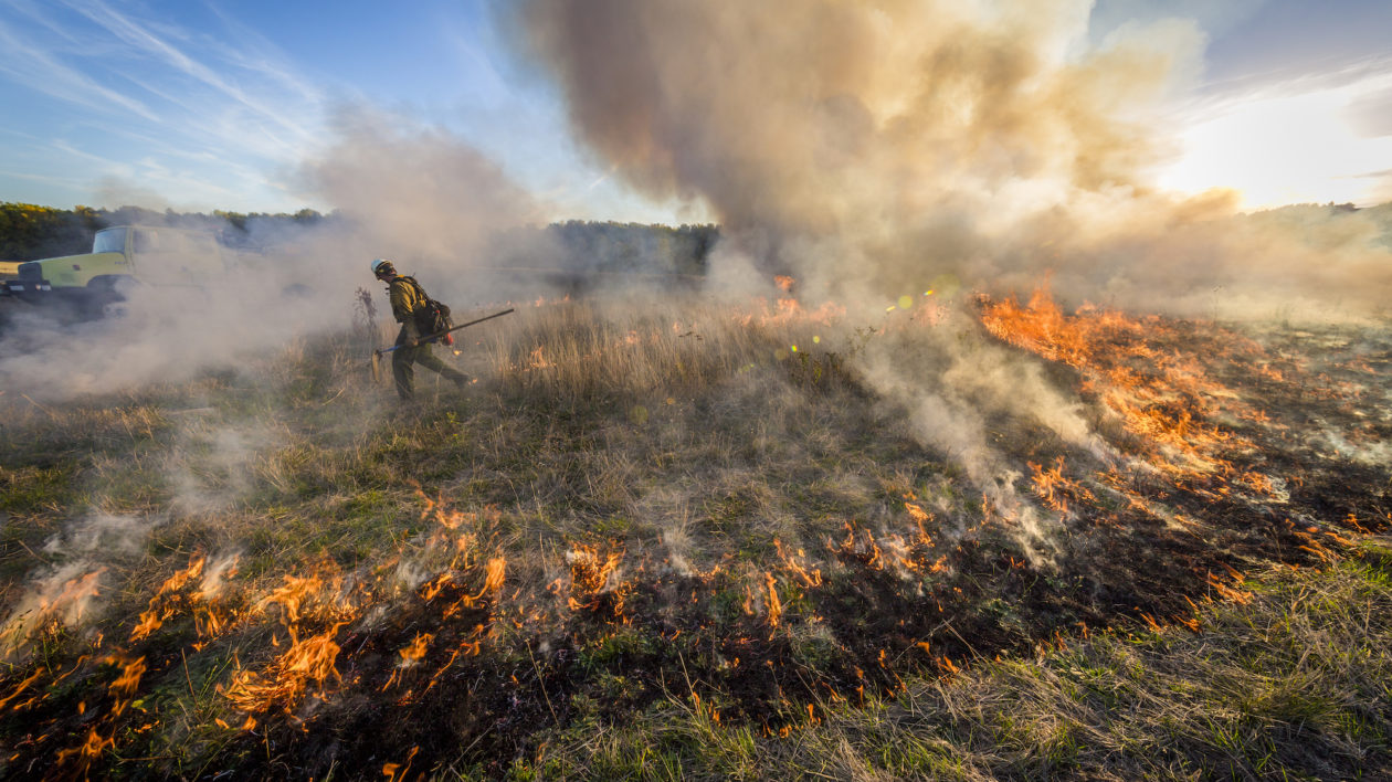 man walking through burning field