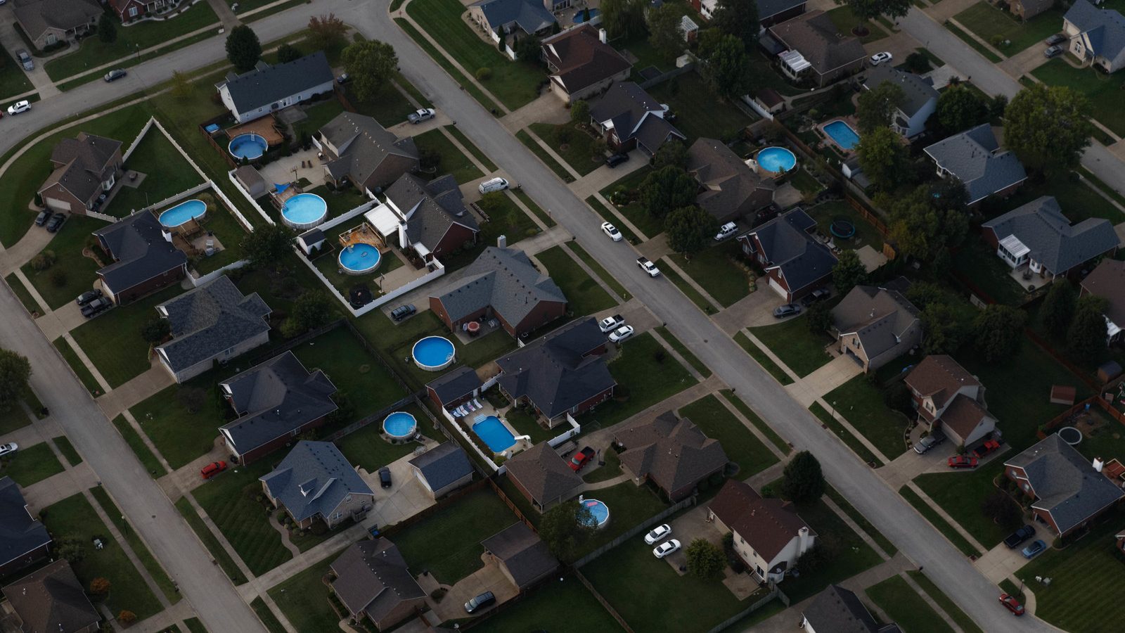 aerial image of housing development showing backyards and a few swimming pools. 