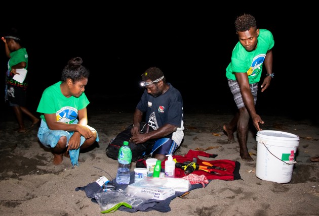 three people on the sand with equitpment