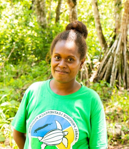 a women looking at the camera and standing in front of trees