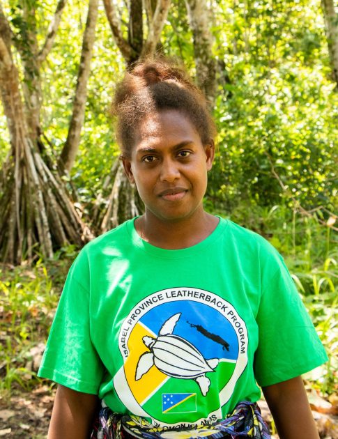 a women looking at the camera and standing in front of trees