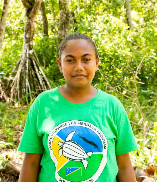 a women looking at the camera and standing in front of trees