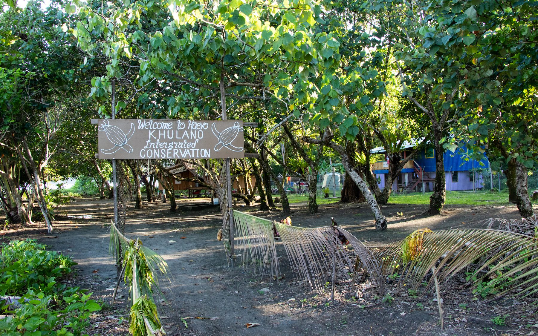 a sign in front of trees and a blue building