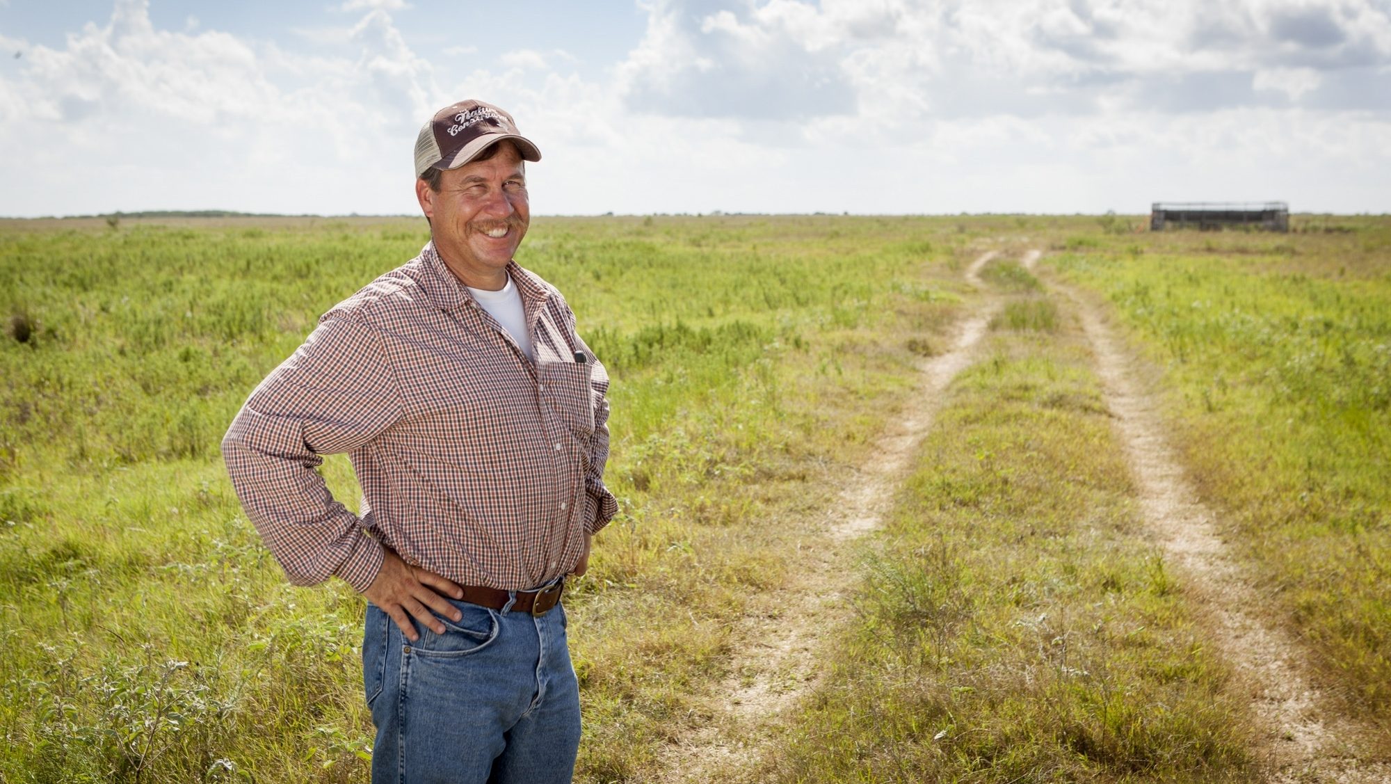 man standing in a grassy field smiling at the camera