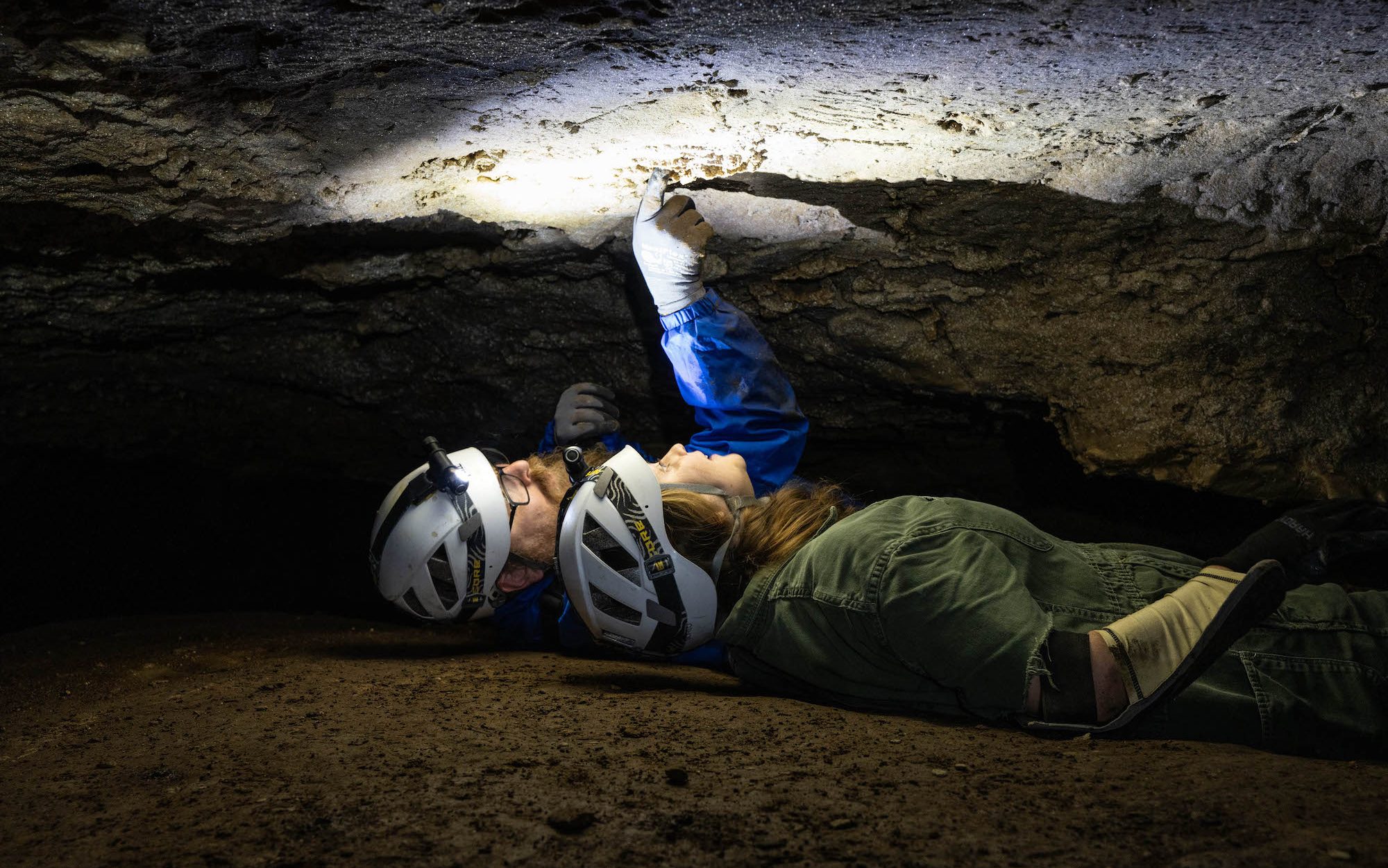 two people lying in a narrow crevice in a cave