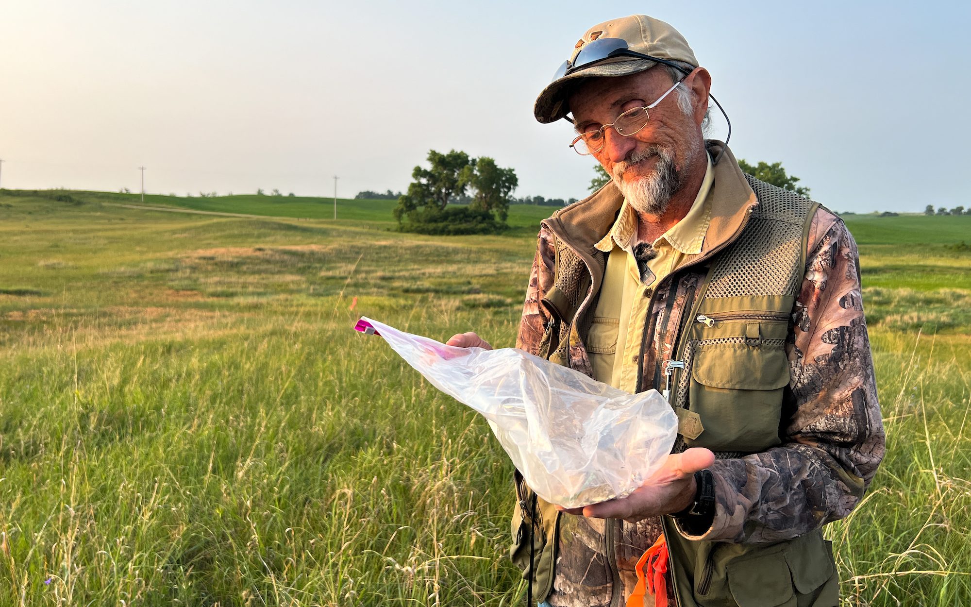 a man in a vest holding a mouse inside a plastic bag