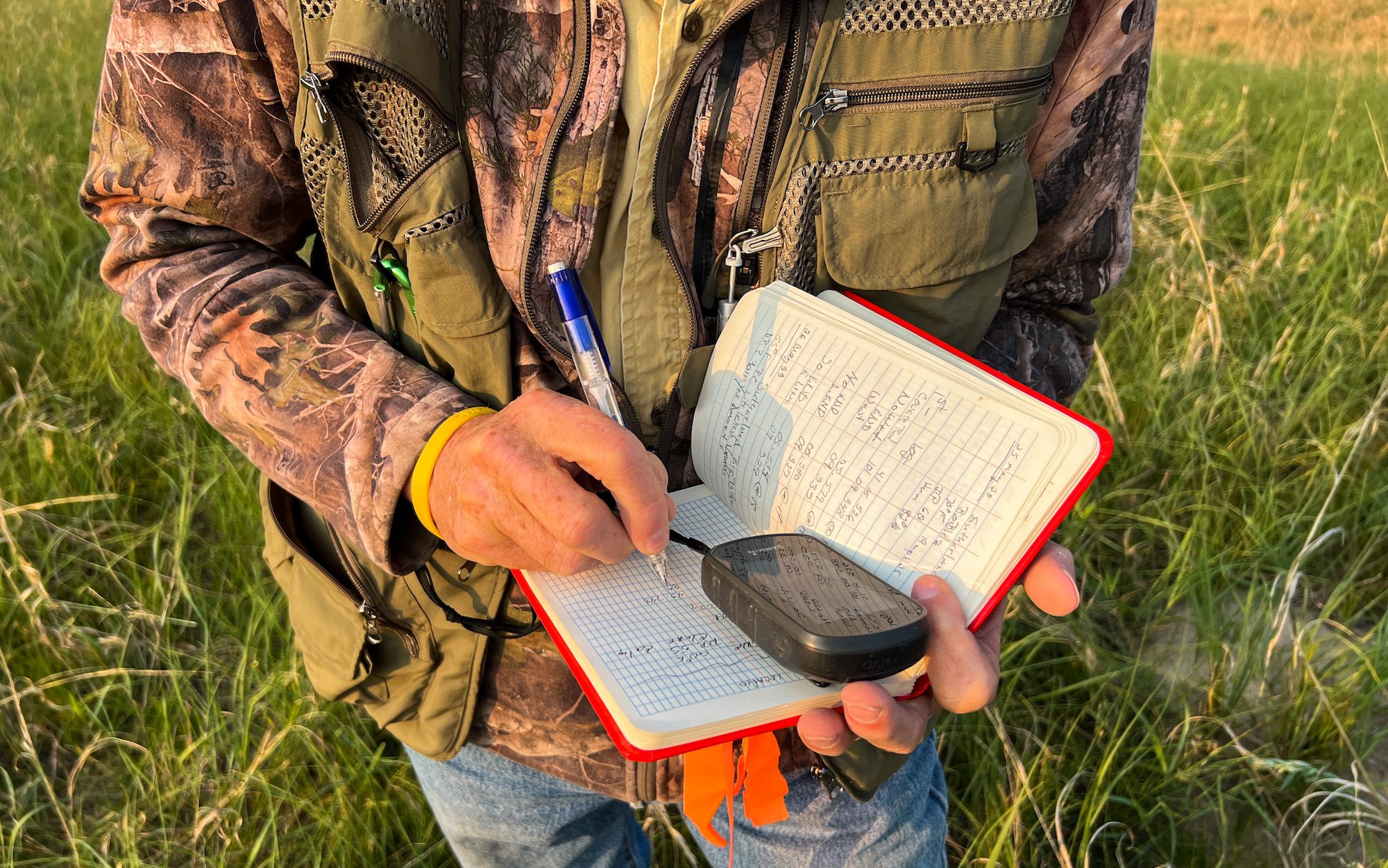 man holding an orange notebook taking notes