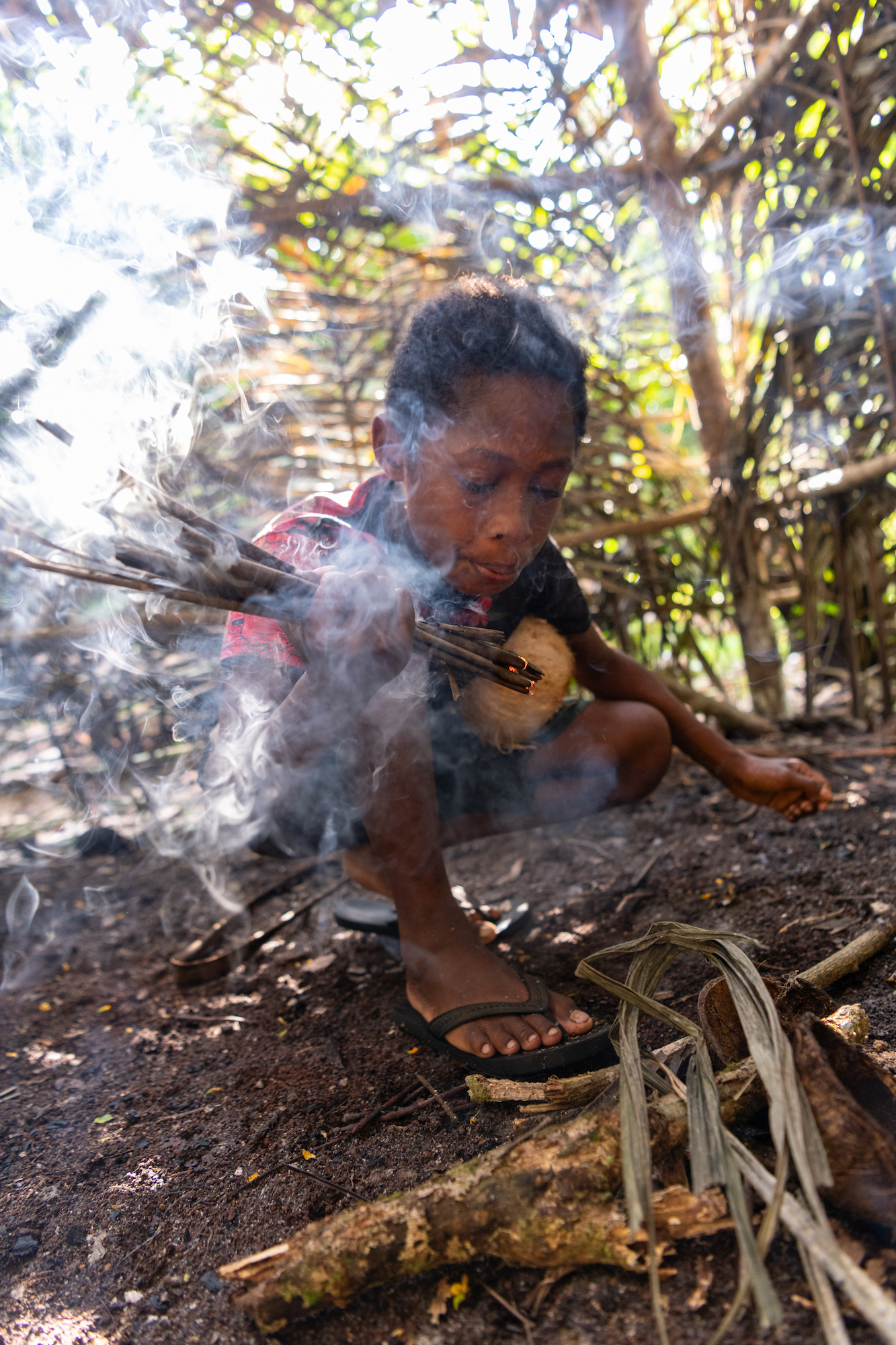 A young boy over a smoking fire