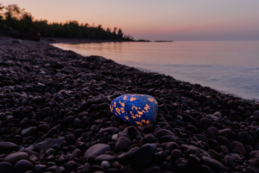 a glowing rock on a lakeshore