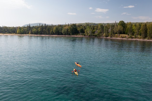 two people kayaking on a blue lake