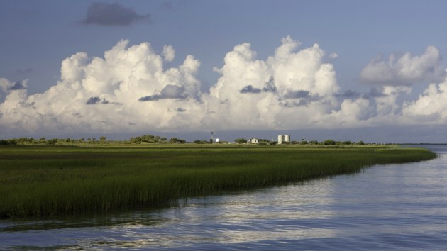 view of coastal estuary with marshland and clouds