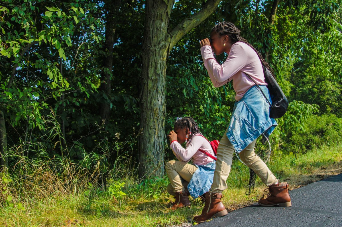 a woman and a girl looking through binoculars on a sidewalk