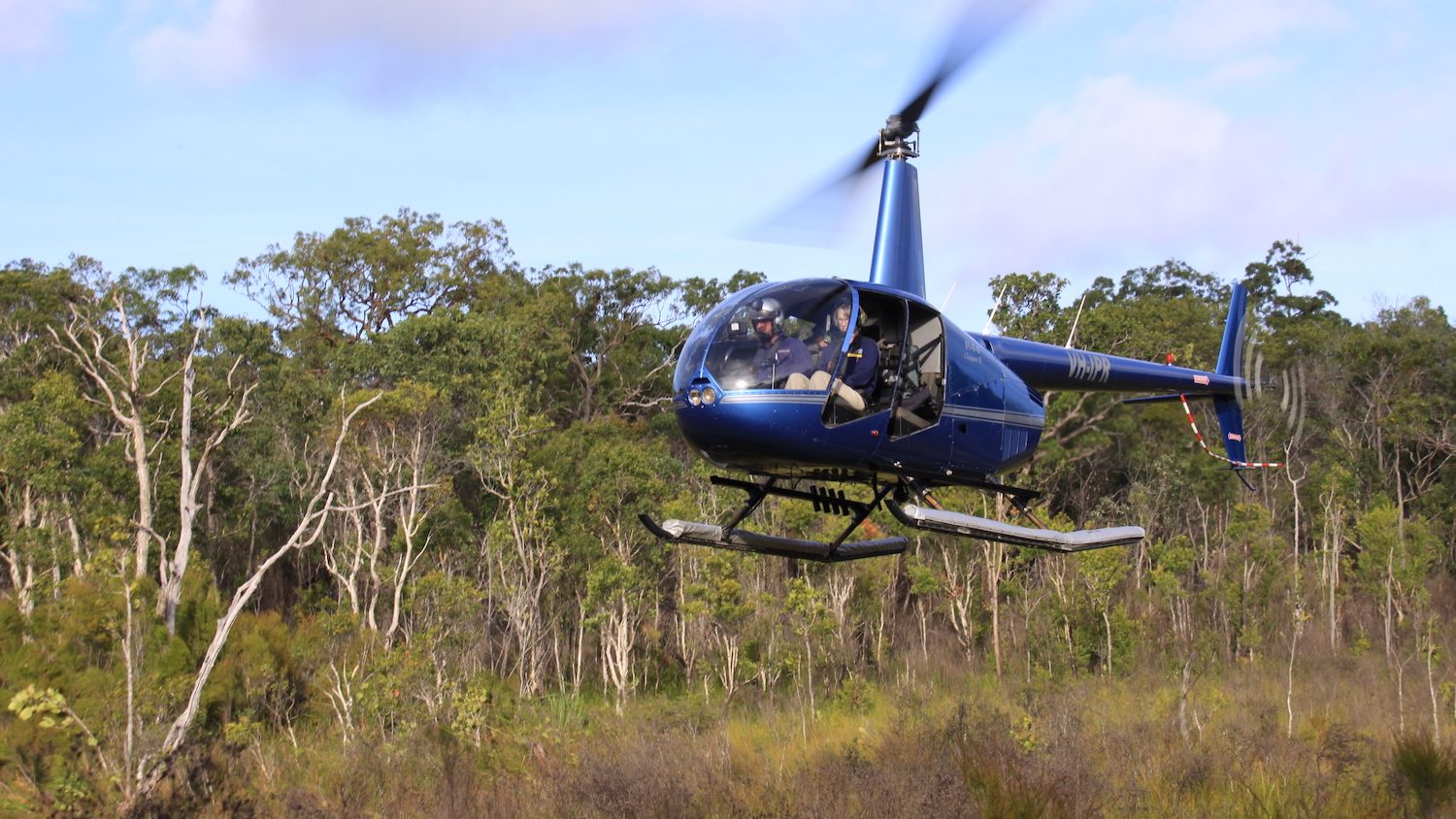 a helicopter landing in front of a forest