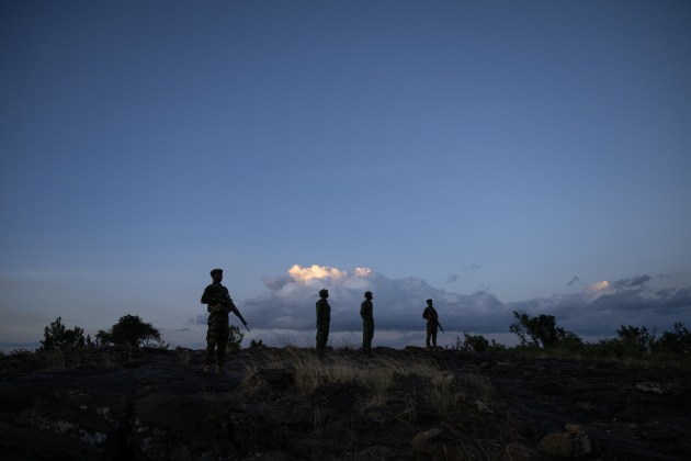Four rangers standing with guns gazing off into the distance. The photo is taken at dawn and you can only see their silhouettes against a backdrop of clouds.