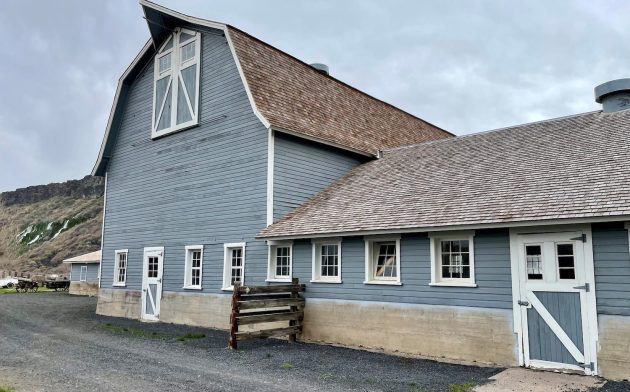 A large wooden gray barn with a brown roof.