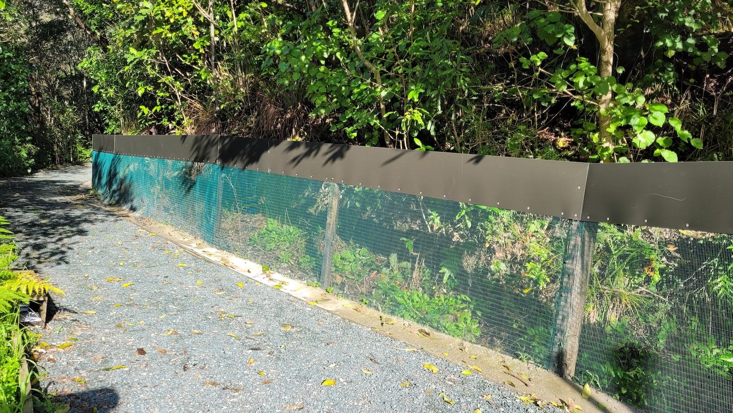View of a gravel path bordered by a low mesh fence.