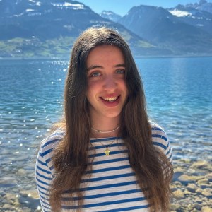 photo of a woman smiling and standing in front of a lake and mountains