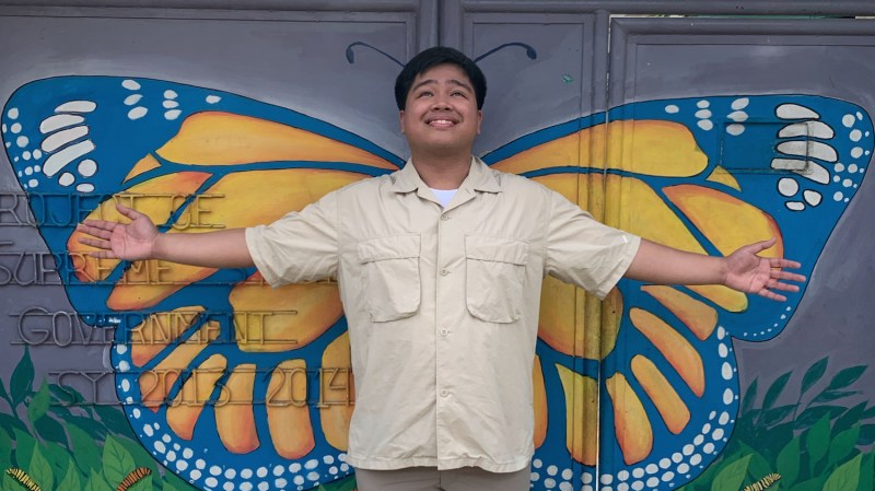 A man standing infront of a mural of butterfly wings