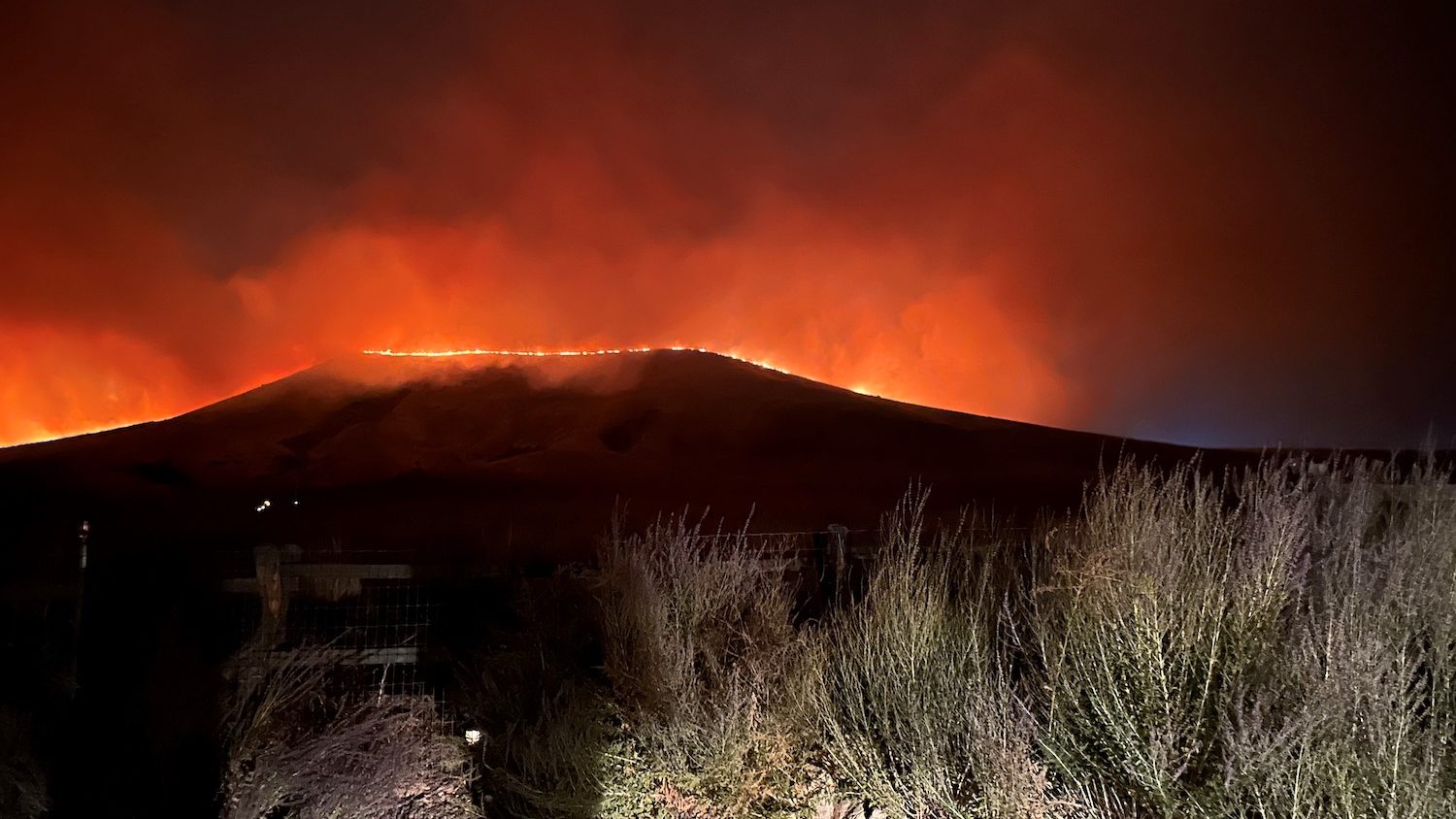 A night photographer of fire burning along a ridge.
