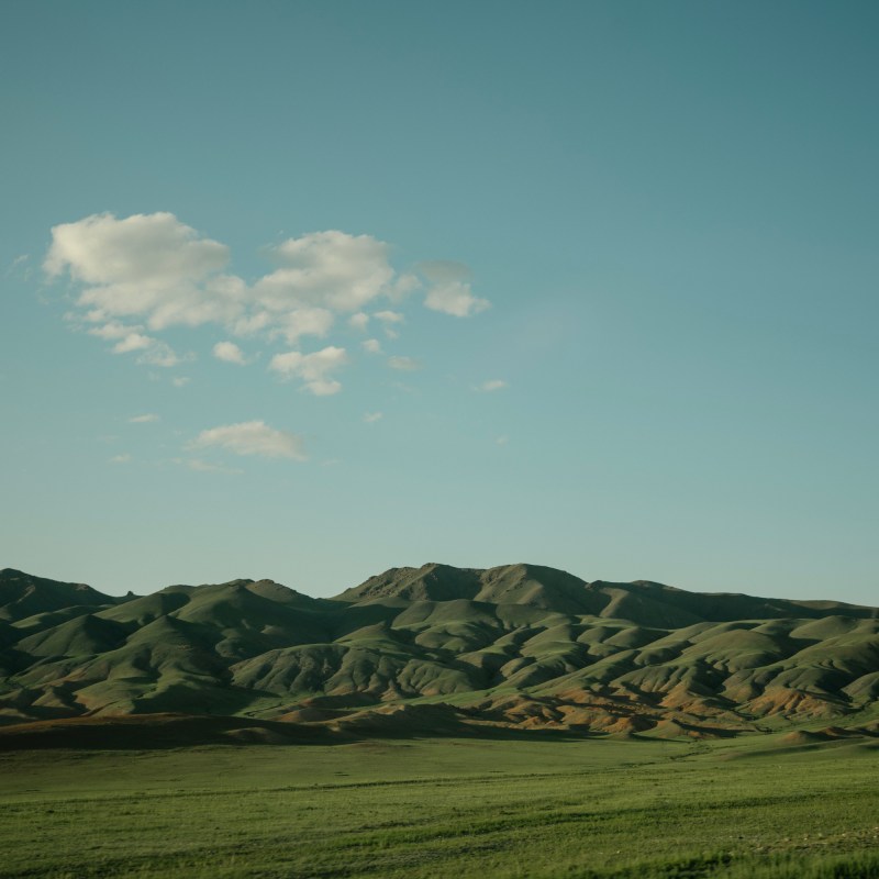 A wide view of grassy Mongolian foothills.
